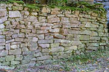 Old mossy stone wall, ancient Central European village, forest background, blurred figure, gap in wall, dawn or dusk lighting. a