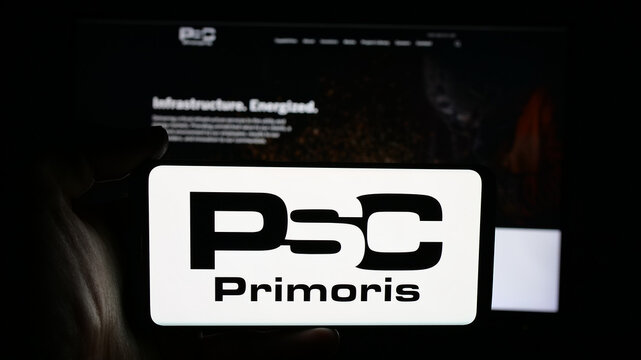 Stuttgart, Germany - 11-20-2025: Person holding cellphone with logo of company Primoris Services Corporation (PSC) on screen in front of webpage. Focus on phone display.