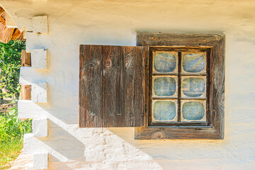 A weathered, white-walled Central European building with a window and shutters, situated in what...