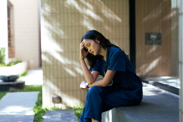 Obraz premium Asian healthcare worker experiencing stress and burnout outdoors