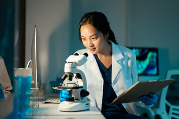 Asian female scientist observing microscope in modern laboratory