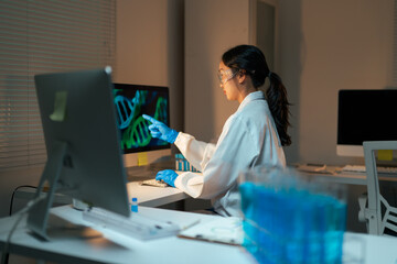 Female scientist analyzing DNA data on computer in laboratory