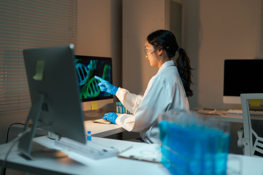 Female scientist analyzing DNA data on computer in laboratory