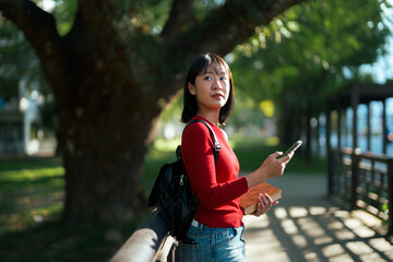 Asian student woman texting with phone in park