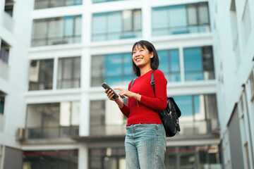 Smiling young woman using smartphone in urban setting