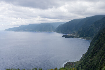 Ribeira da Janela coast seen from the highlands near Fanal on Madeira, dark emerald cliffs meet the calm Atlantic under layered clouds