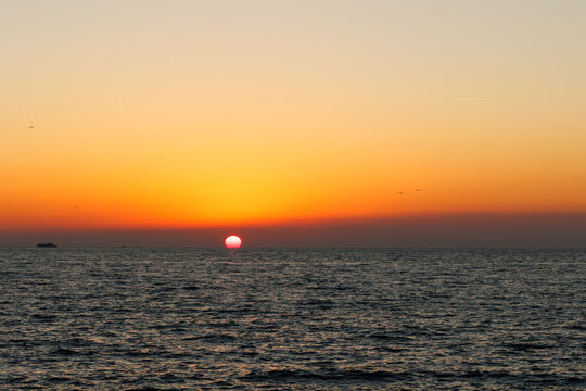a red sun at sunset on the sea with orange sky