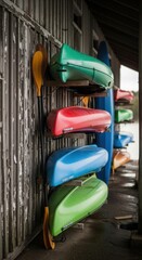 Brightly colored kayaks and canoes stored vertically on a weathered wooden wall anticipating thrilling outdoor water activities