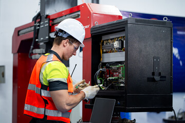 A man in a yellow and black safety vest is working on a machine