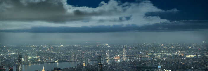 Obraz premium Drone panorama of Manhattan cityscape illuminated by evening lights after sunset over New York City