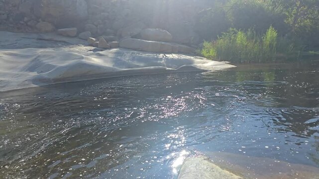 Tule River river flows over smooth rocks under sunlight.