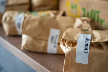 Close-up of brown paper bags with meal kits labeled Recept or Recipe. Subscription-based food delivery sorted by recipes.