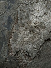 Broken concrete revealing rough soil beneath, showcasing cracked edges, scattered debris, and a rugged surface texture.