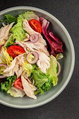 Salad chicken meat and vegetables tomato, green leaf lettuce, onion natural product tasty snack fresh delicious gourmet food background on the table rustic top view copy space keto and paleo diet