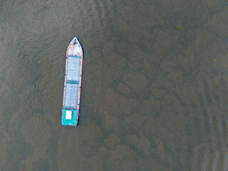 Boat is floating in the water. The boat is green and white. The water is brown