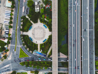 A city street with a park and a bridge. There are many cars and people on the street
