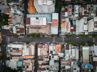 A city street with many buildings and cars. The street is lined with trees and has a crosswalk