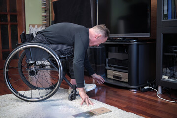 A man in a wheelchair leaned over and prepared to turn on a CD player.