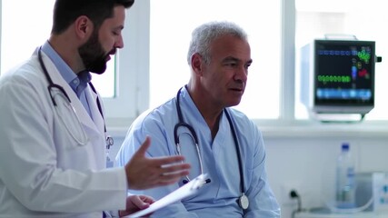 Two medical professionals discussing patient data, with a monitor displaying vitals - Powered by Adobe
