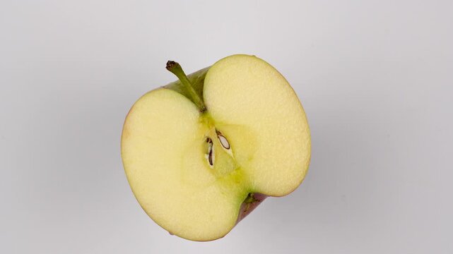 Top view of a fresh apple cut in half rotating. Healthy organic fruit cross-section with seeds and stem isolated on white background. Diet concept.