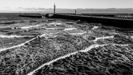 Aerial black and white view of the piers and lighthouse at Whitby
