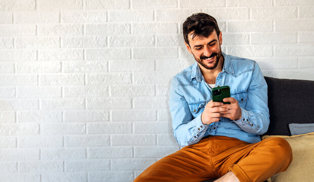 Smiling man enjoys digital chatting, mobile communication at home, staying connected with friends