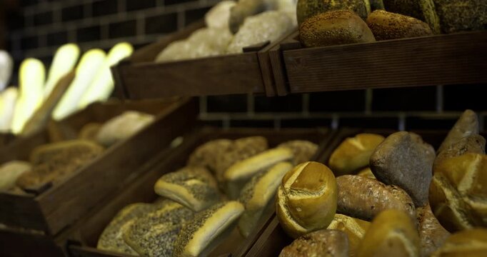 Various types of artisanal breads are arranged in wooden trays, showcasing a range of textures and colors. The warm atmosphere highlights the quality of the baked goods.