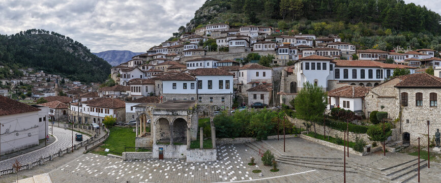 Scenic view of Berat&rsquo;s hillside homes and historic stone architecture rising above the old town square under cloudy skies.