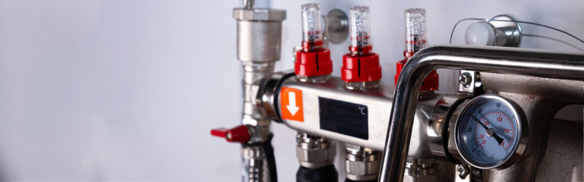 Complex residential heating manifold system with valves, gauges, and piping network. banner