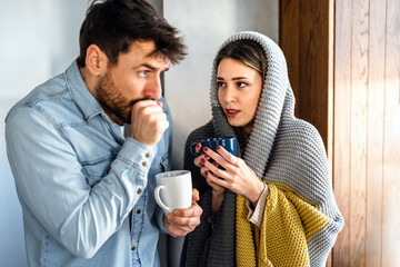 A couple wrapped in blanket enjoys a quiet moment indoors, finding warmth and calm at home