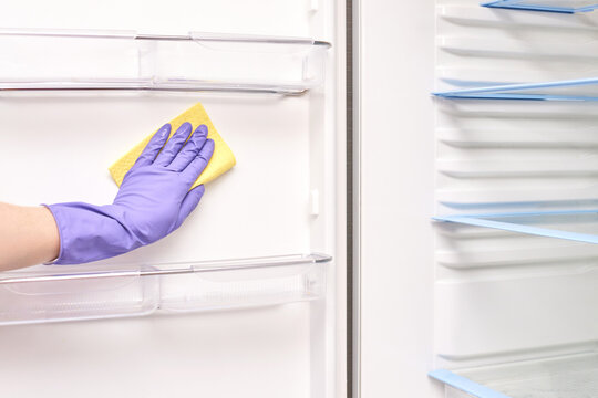 Cleaning inside a refrigerator with gloved hand using yellow cloth for hygiene and organization. - Powered by Adobe