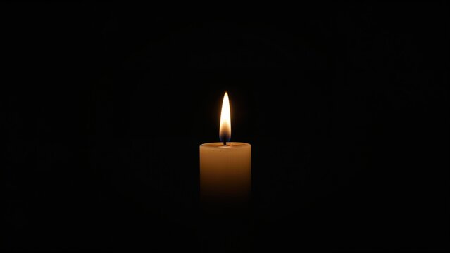 A single candle with a flame illuminated in darkness. Concept of hope and remembrance. Light in the darkness. The symbol of reflection and serenity.