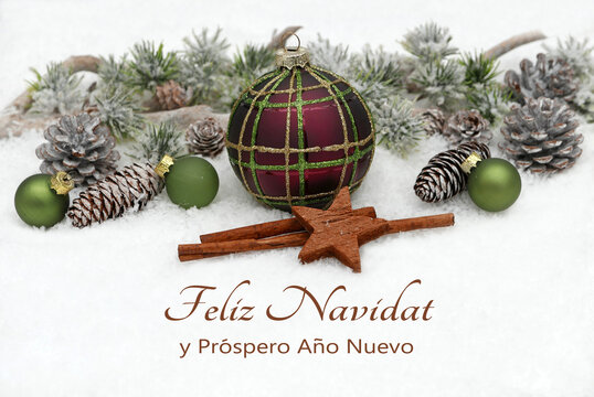 Tarjeta navideña: Paisaje invernal con adornos navideños y ramas de abeto sobre la nieve. La frase "Feliz Navidad y próspero Año Nuevo" está escrita en la nieve.