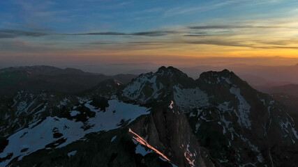 Rocky snow mountains at sunset aerial
