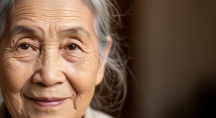 Close-up of elderly Asian woman with natural wrinkles and soft smile, warm daylight, minimal retouch, calm mood, negative space on the right