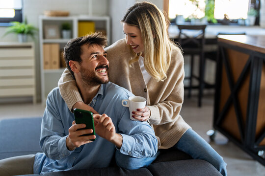 Happy couple using smartphone for social media mobile banking and modern digital lifestyle together - Powered by Adobe