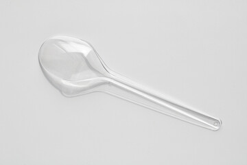 A clean transparent plastic spoon on a simple white background.