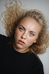 Young Woman with Curly Hair and Striking Blue Eyes on Neutral Background