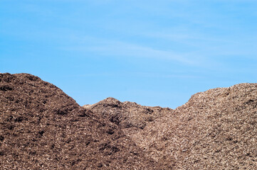 mountains of wood chips against a blue sky
