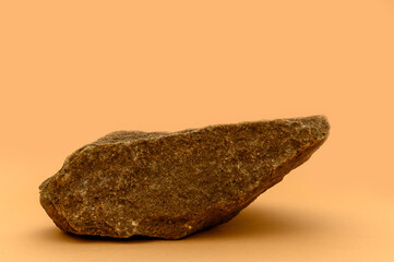 A large brown stone on a beige background. Product display podium.