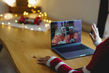 Young woman doing videocall with parents using laptop at home during Christmas day - Distance, family love and technology concept - Focus on left hand