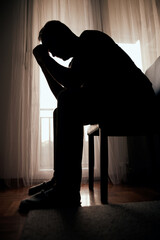 Silhouette of depressed, sad and lonely man in the apartment.