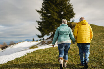 Happy senior couple walking in nature during winter season - Elderly pensioner people, active lifestyle and love concept