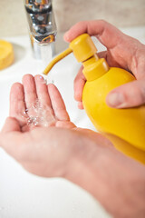 Human hands are turning the home faucet on and washing it with soap and clean tap water for good personal hygiene.