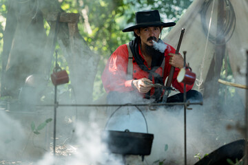 A cowboys preparing food at a campfire, roasting meat together in a warm