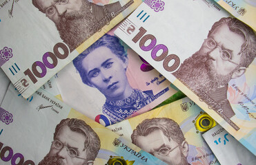 Multiple Ukrainian banknotes showing different denominations and historical figures on a colorful surface