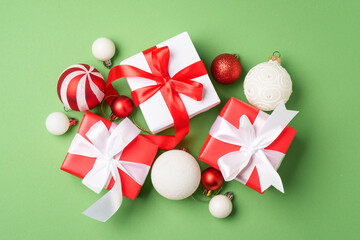 Christmas gift box and holiday decorations at green background.