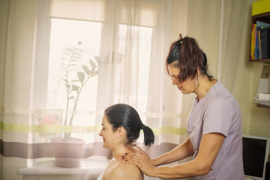 A female masseuse a neck and collar massage at home. A female masseuse performs a relaxing neck and collar zone massage at home. The scene shows gentle manual therapy, wellness care, and stress relie