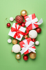 Christmas gift box and holiday decorations at green background.