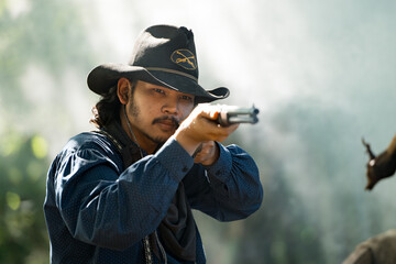 A cowboy aiming rifle in a forest camp, with sunlight streaming through the smoke